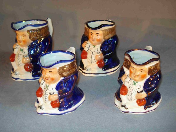 SET OF TOBY MUGS: A set of four Toby mugs, all in the same form but graduated in size. Features colorful glazes of dark blue, iron oxide (red), green, black, brown, and flesh in copper luster. the tallest is 6" in heig
