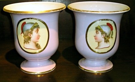 Porcelain garnitures: A pair of 7 1/2" porcelain urns with a Classical theme. Note: one has had the base repaired long ago- see detail photo
