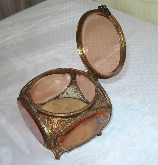 Jewelry box: A bevel glass and gild toned Victorian jewelry box whose lid opens upward to a cushioned interior.