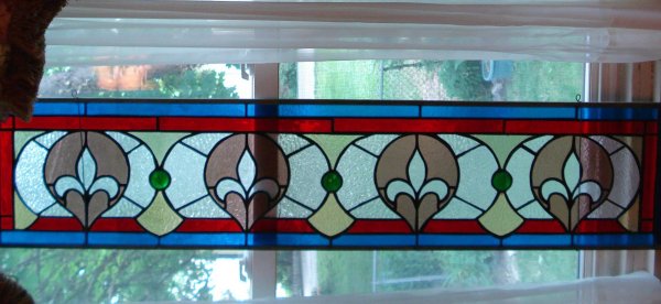Stain glass art: A "transom" 48 1/2" X 10 5/8" stain glass example featuring the trefoil pattern. Comes with custom made board for mounting to make shipping easier and safer.