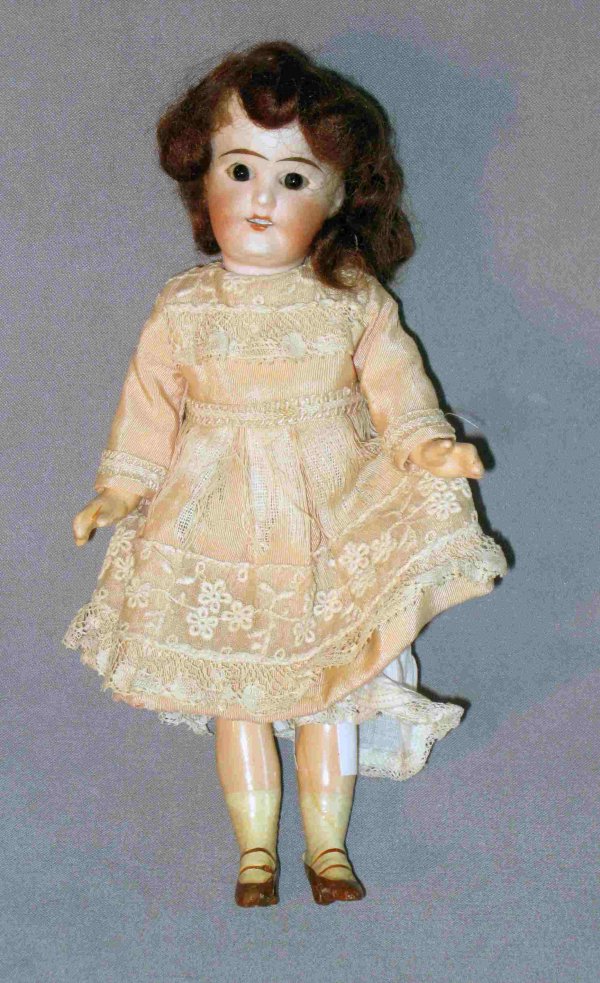 Antique doll: A 7 1/2" ceramic doll with glass dark blue eyes, auburn hair and lace dress, undergarments. In good condition except she needs a hairdo.