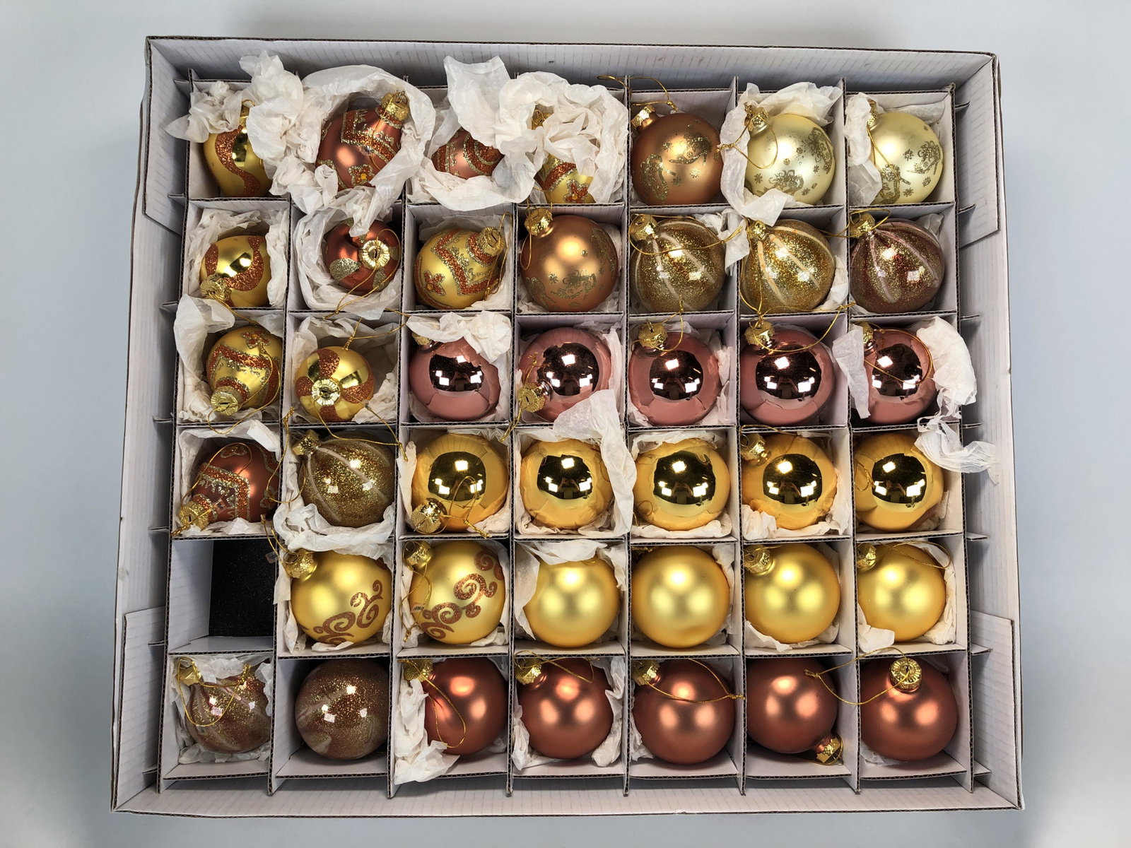 LOT OF CHRISTMAS TREE ORNAMENTS IN STORAGE BOX: LOT OF CHRISTMAS TREE ORNAMENTS IN STORAGE BOX 41 glass ball ornaments in a storage box. Several different designs in shades of mauve, yellow, gold and orange. Glittery designs cover