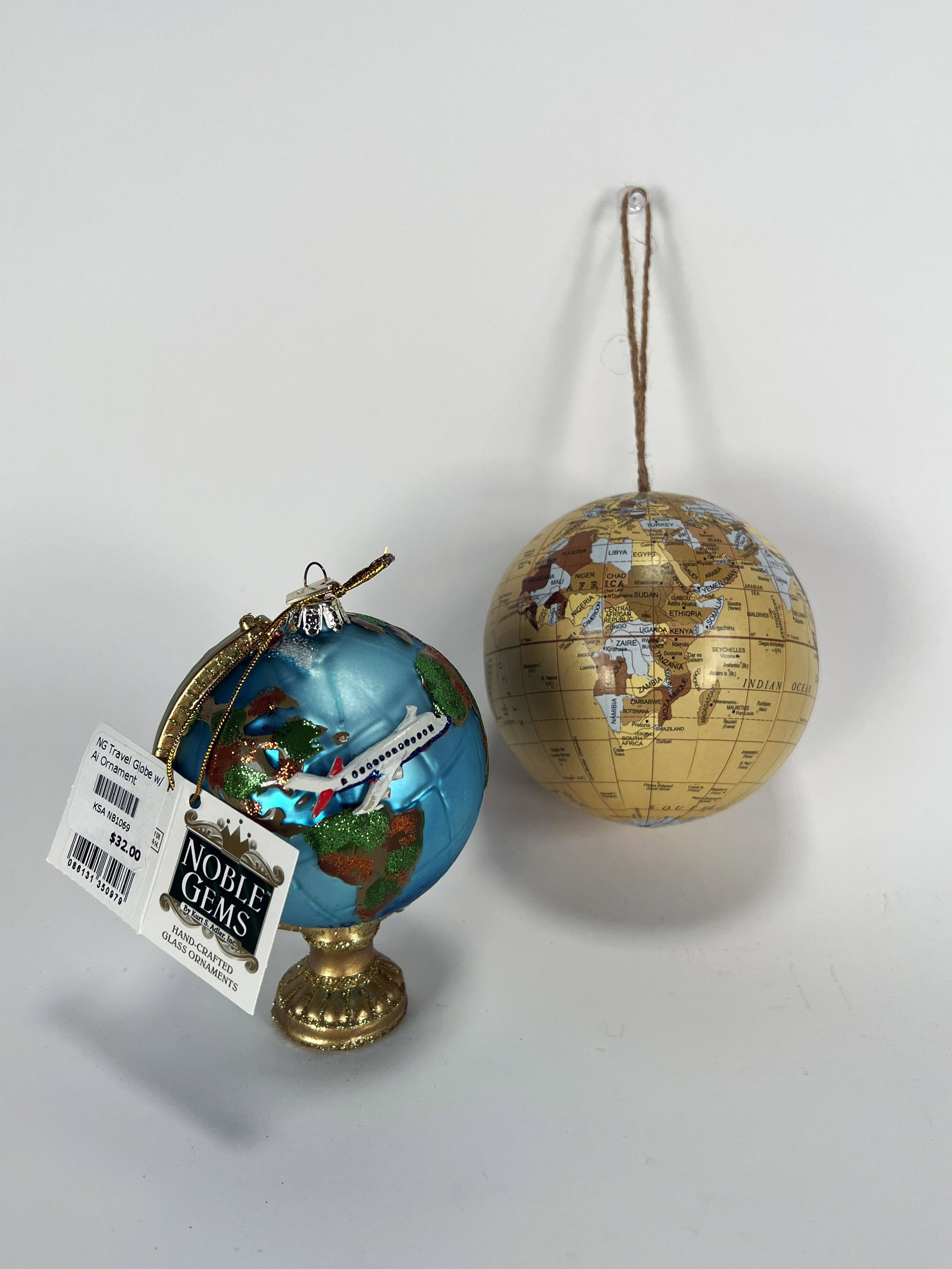 TWO TRAVEL GLOBE CHRISTMAS ORNAMENTS: TWO TRAVEL GLOBE CHRISTMAS ORNAMENTS One marked Nobel Gems by Kurt S. Adler Travel Globe with Airplane Ornament. Says Bon voyage with glitter accents. One world globe in neutral colors w