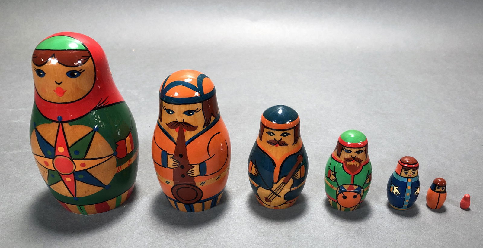 SIX PIECE MATRYOSHKA FAMILY NESTING DOLLS: SIX PIECE MATRYOSHKA FAMILY NESTING DOLLS Hand painted birchwood. Largest doll has compass star on belly, inside three men playing instruments, and two children. Has USSR handicraft stic