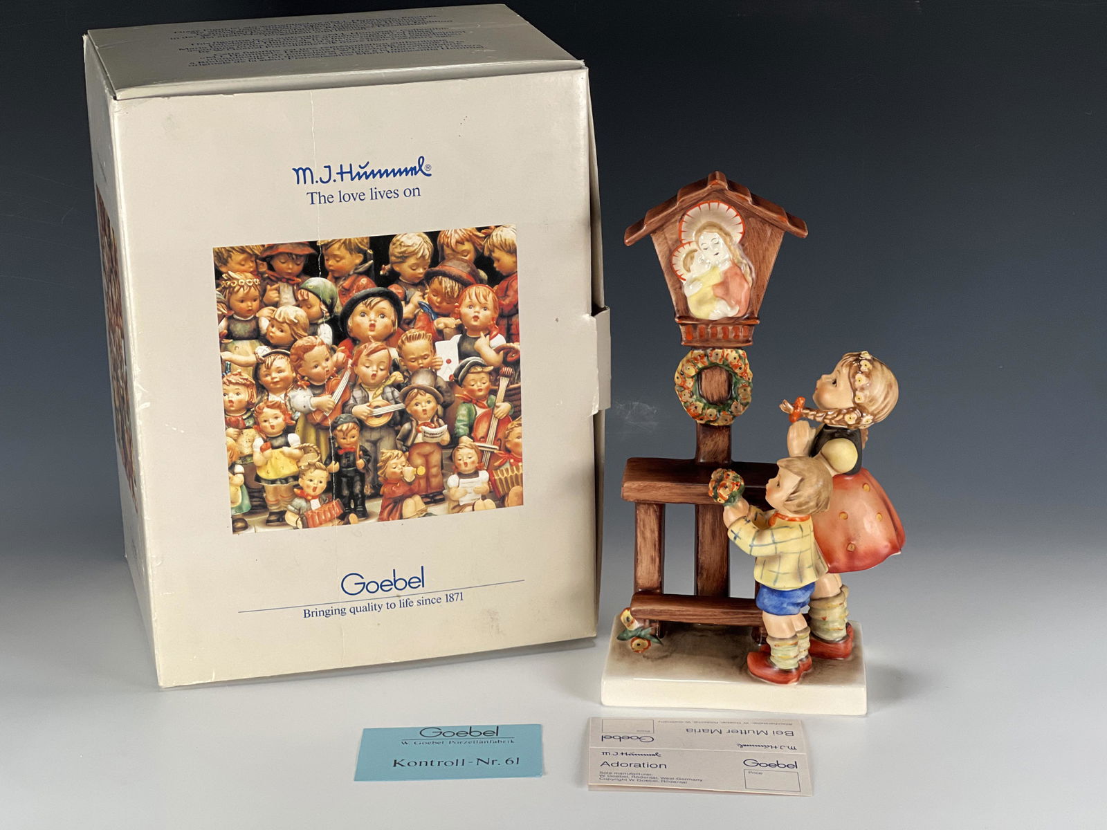 GOEBEL HUMMEL ADORATION FIGURE IN BOX: GOEBEL HUMMEL ADORATION FIGURE IN BOX Two children stand with hands in prayer at a plaque of Mary and Jesus. TMK - 6. Artist signed. Marked on bottom. In original box.