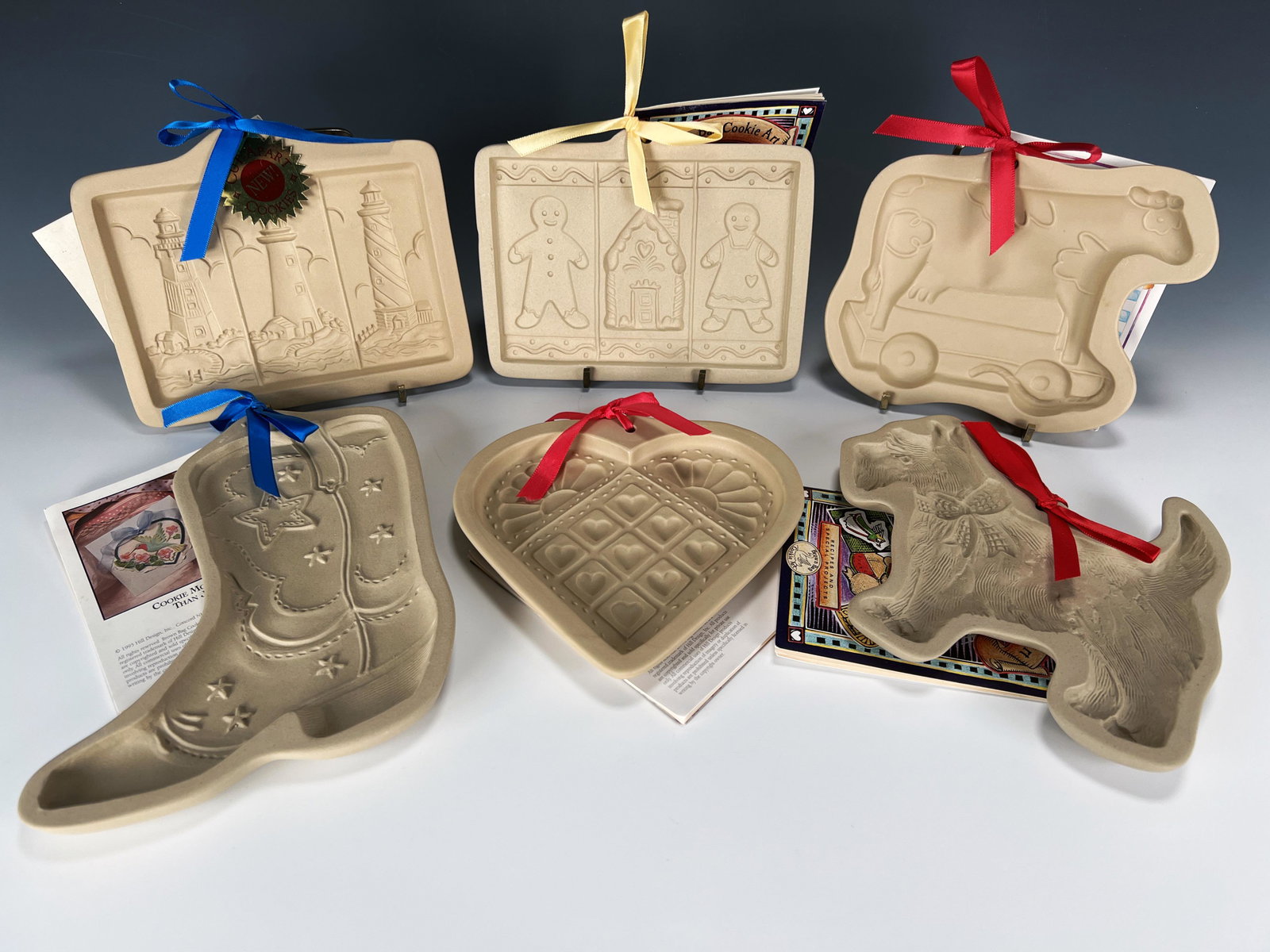 LOT OF CERAMIC COOKIE MOLDS BROWN BAG ART: LOT OF CERAMIC COOKIE MOLDS BROWN BAG ART Cowboy boot, Gingerbread boy and girl with house, Scottie dog, lighthouses, heart quilt, and toy cow. All with original tags.