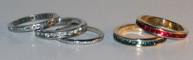 Five rings: Stack and pack them......the more the merrier. Five gold wedding bands. One having mounted rubies, another with sapphires, and three with diamonds (one damaged and missing stones).