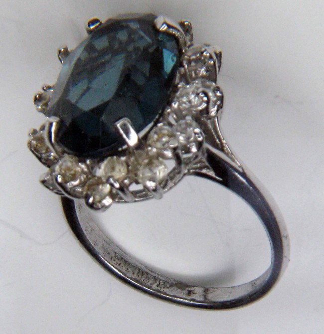 Attractive shapphire & diamond cocktail ring: A large cocktail ring with a blue glass mounted sapphire surrounded by paste diamonds in a silver setting.