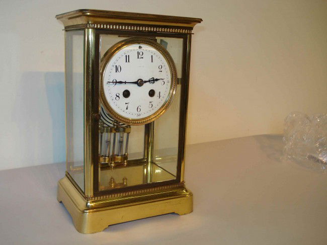 Bevel glass and brass French clock: A brass and bevel glass cased French made mantel clock with a Mercury compensated pendulum, white porcelain dial.