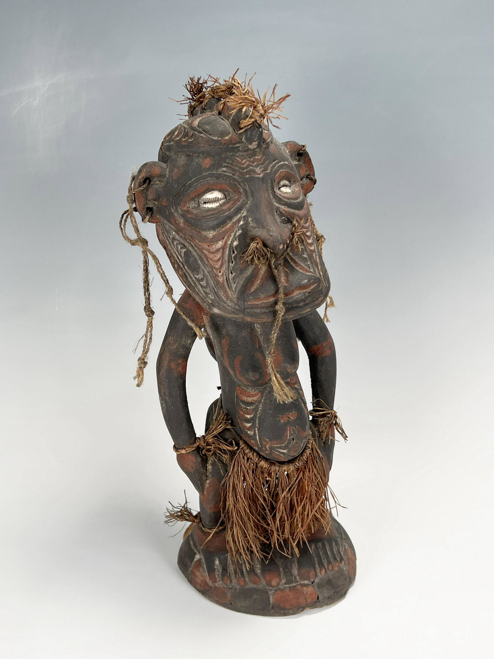 AFRICAN FERTILITY FIGURE: AFRICAN FERTILITY FIGURE Fiber skirt and hair embellishment, Painted scarification designs, piercings, and applied conch shell eyes. 5" X 13"
