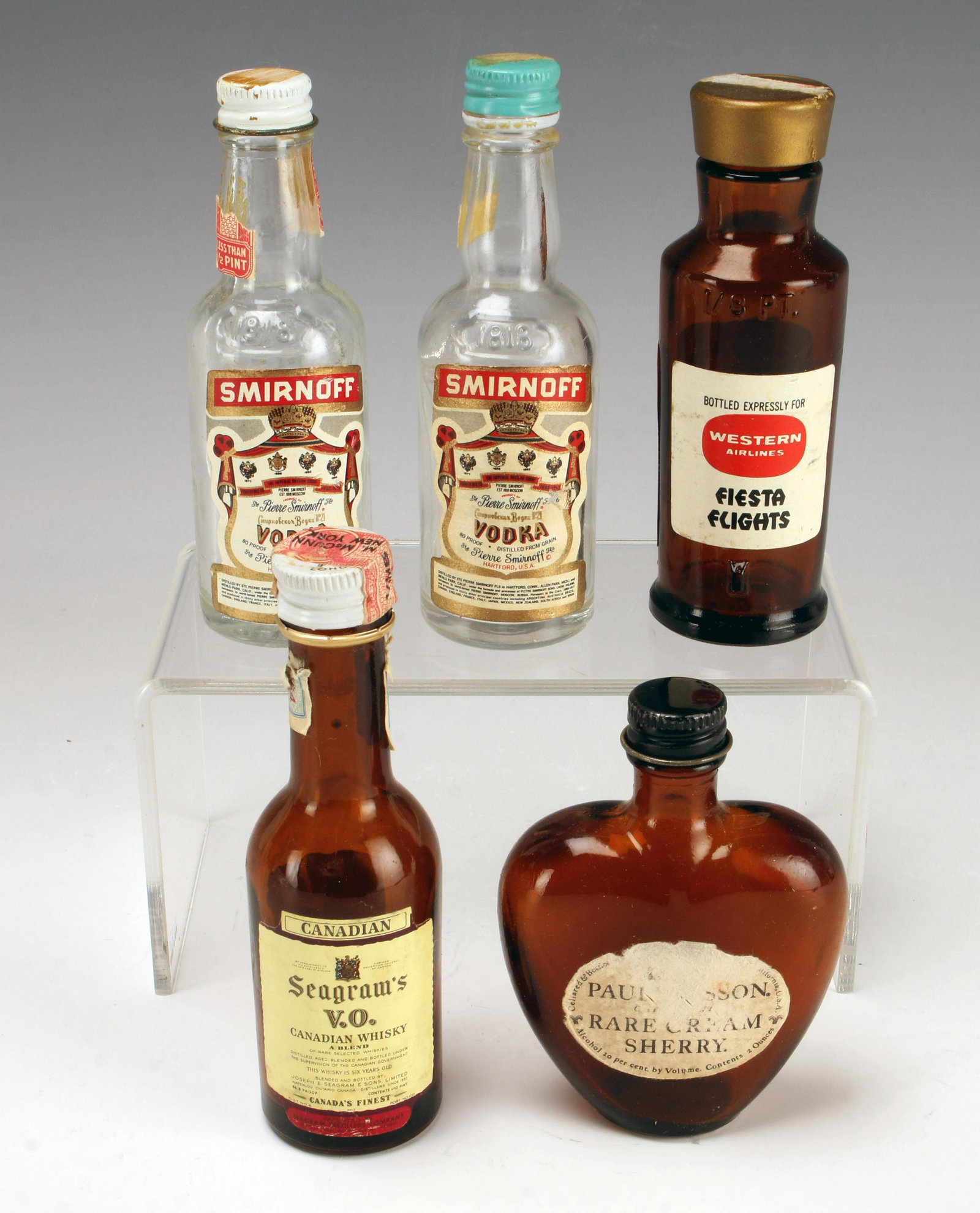 VINTAGE GLASS MINIATURE NIP AIRPLANE BOTTLES: VINTAGE GLASS MINIATURE NIP AIRPLANE BOTTLES Including Paul Masson Rare Cream Sherry, Seagram's V.O. Canadian Whiskey, Heublein Full Strength Vodka Martini, and two Smirnoff bottles. Al