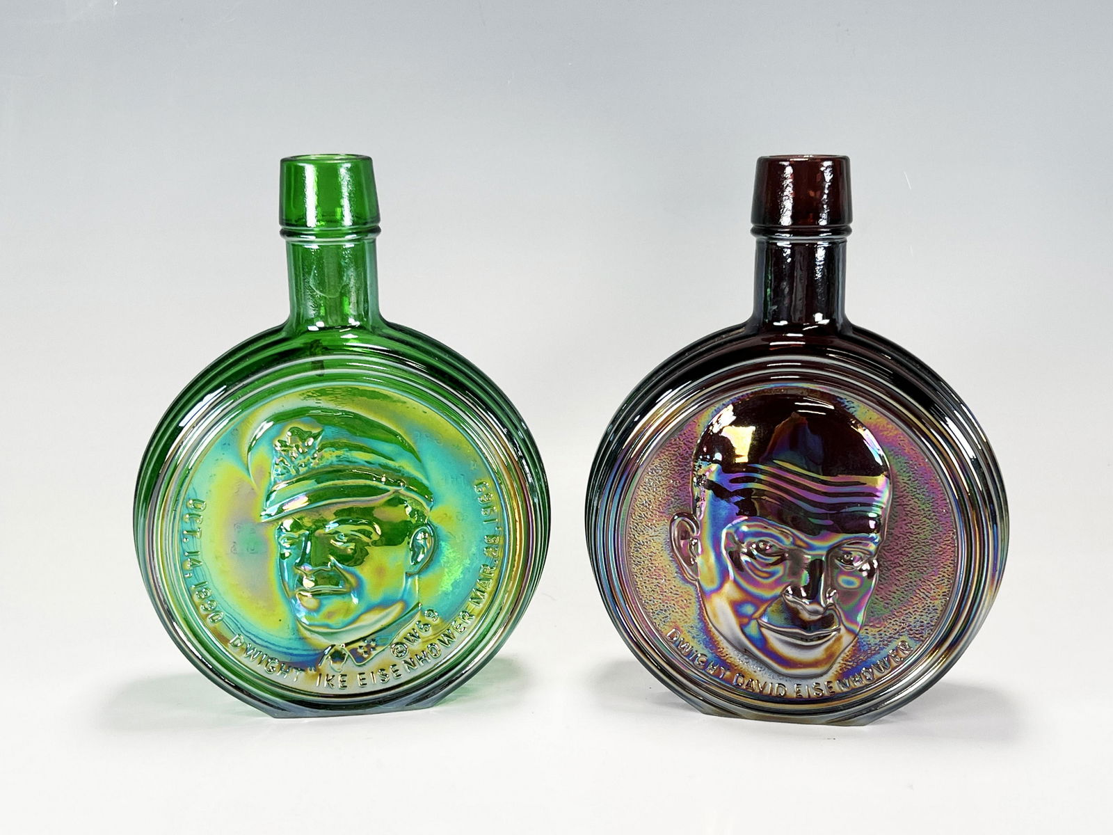 WHEATON FIRST EDITION COMMEMORATIVE EISENHOWER BOTTLES: WHEATON FIRST EDITION COMMEMORATIVE EISENHOWER BOTTLES Green and purple iridescent glass bottles with the profile of Eisenhower of both. Marked Wheaton First Edition on bottom.