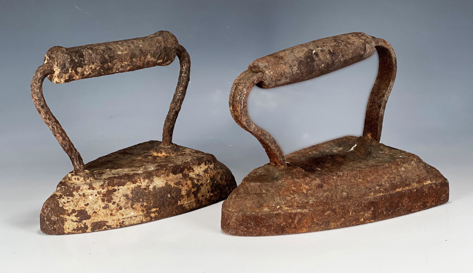 TWO CAST IRON IRON DOORSTOPS: TWO CAST IRON IRON DOORSTOPS Two cast iron irons doorstops in triangle shape. Both have patina. 7 1/2" X 5" Shipping: