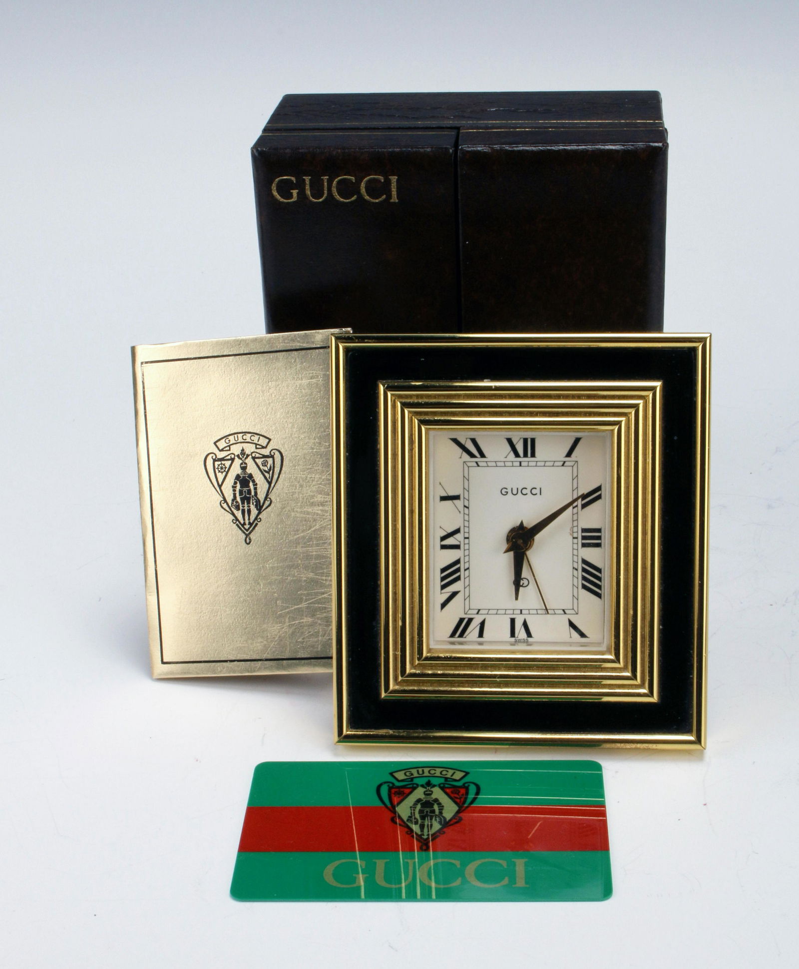 GUCCI MENS BLACK TRAVEL ALARM DESK CLOCK IN BOX: GUCCI MENS BLACK TRAVEL ALARM DESK CLOCK IN BOX Heavy, solid rectangular clock with black and enamel and brass. Hinged kick stand. In original box, with paperwork. Snap broken on ca