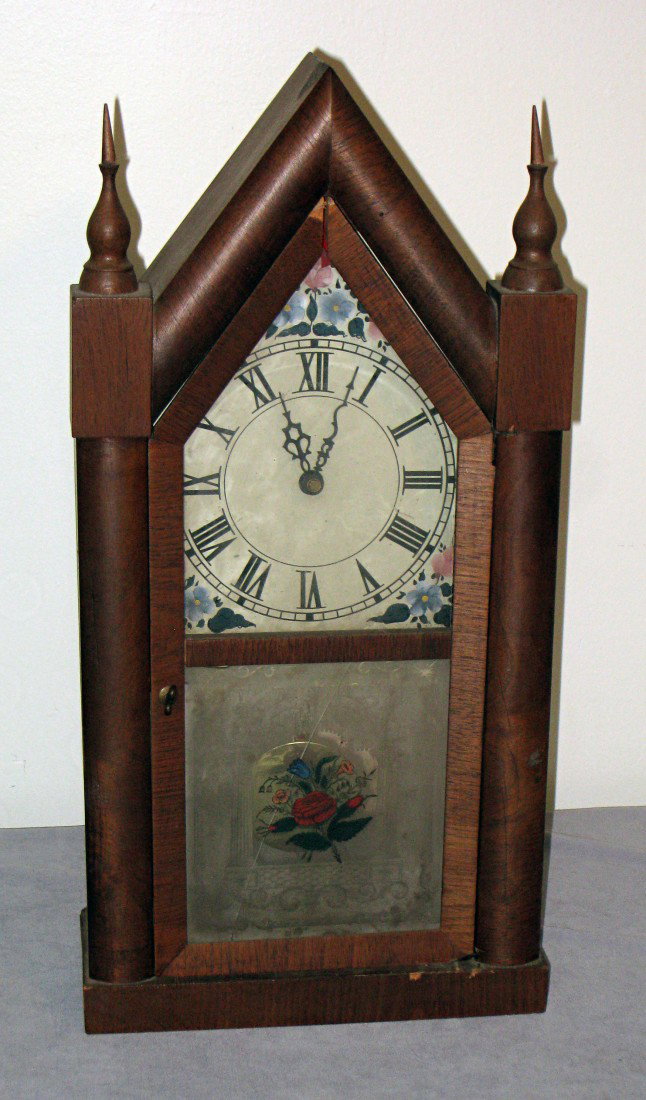 Quartz Steeple Clock: An American 19th century steeple or sharp Gothic clock. The rosewood veneered clock has its original reverse painted glass, although now with a diagonal break across. Someone has removed the backboard