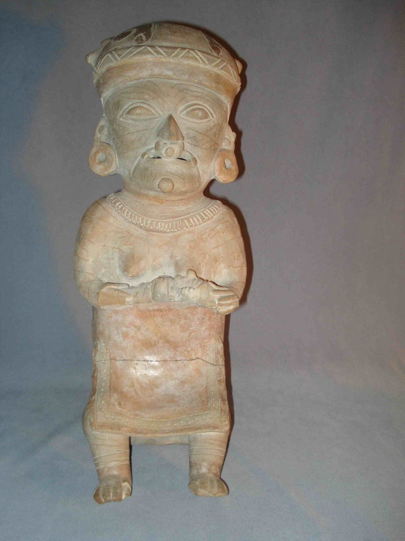 Pre-Colombian Woman With Babe: A painted clay primitive figure of a woman nursing a baby, about 14 1/2" in height and 6 1/2" deep. Traces of paint survive. The head is presently detached (broken off ) and we have not attempted to r