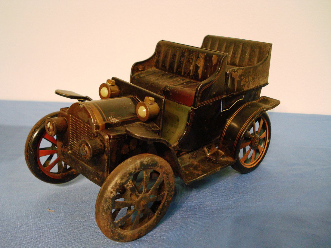 Model Car: A pressed tin and painted model old time car. The condition is fair considering the loss of some paint flaking, and a few dents and the fact that the crank clockworks mechanism is not really operating