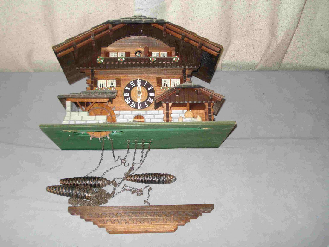 Chalet Cuckoo Clock: A chalet cuckoo clock with animation on the strike when the bird comes out and with three weights. The clock is 13" X16". Has three weights, pendulum, and a lower part of the case needs regluing.