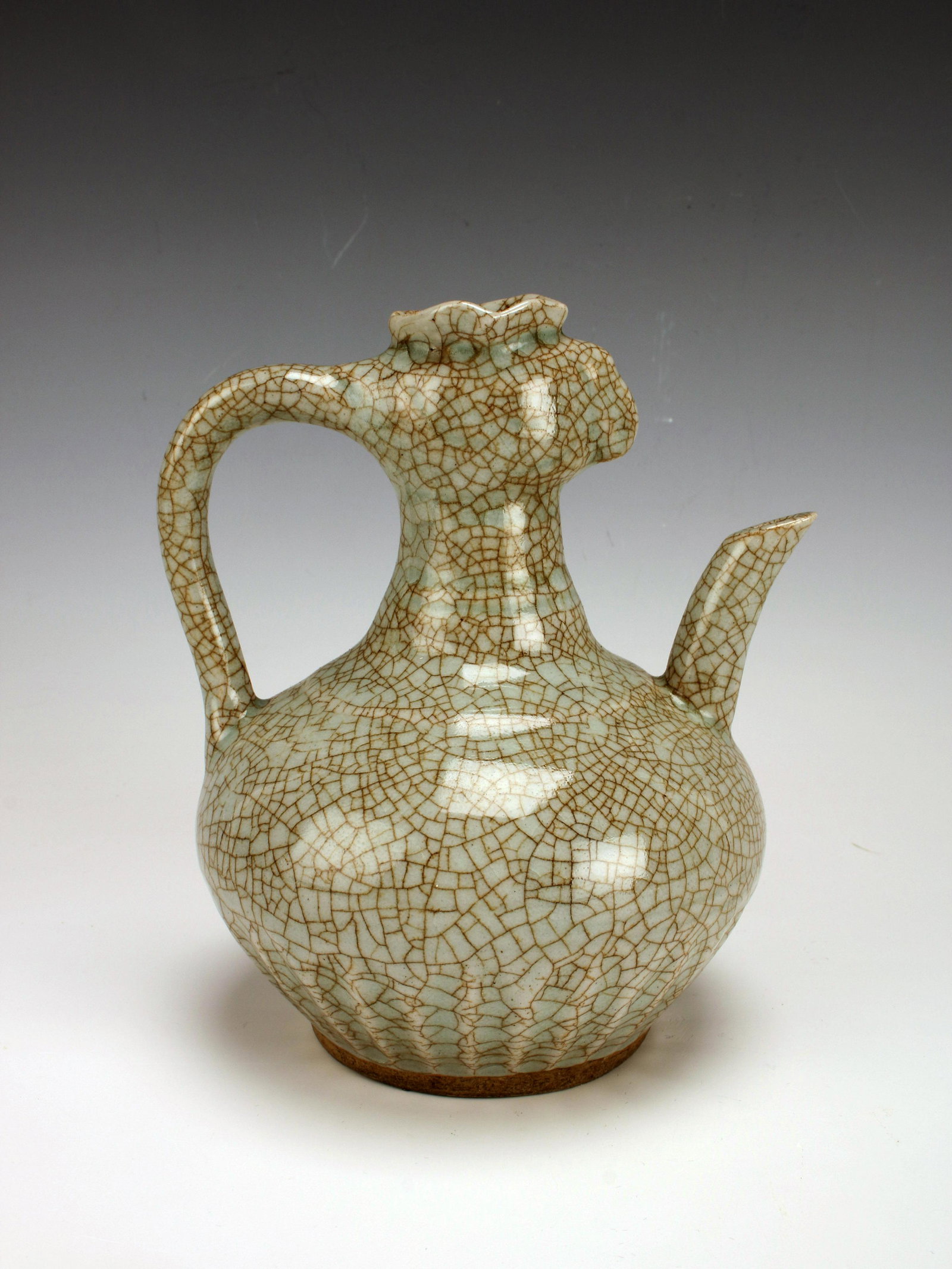 PALE CELADON CRACKLE PHOENIX PITCHER: PALE CELADON CRACKLE PHOENIX PITCHER Looped handle attaches the phoenix head rim to the round body. Unglazed bottom. 6" X 6 1/2"