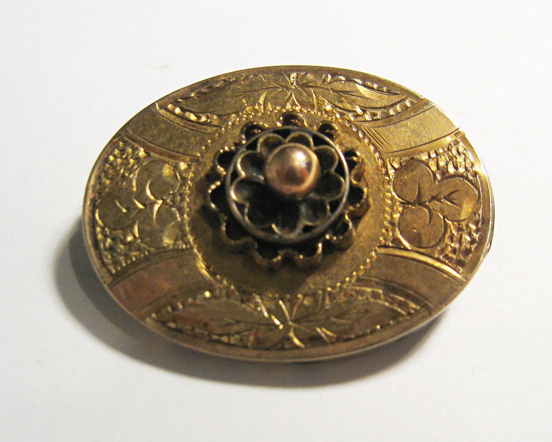Gold Pin: An 21 MM X 28 mm oval shaped and engraved antique pin with a central rosette.