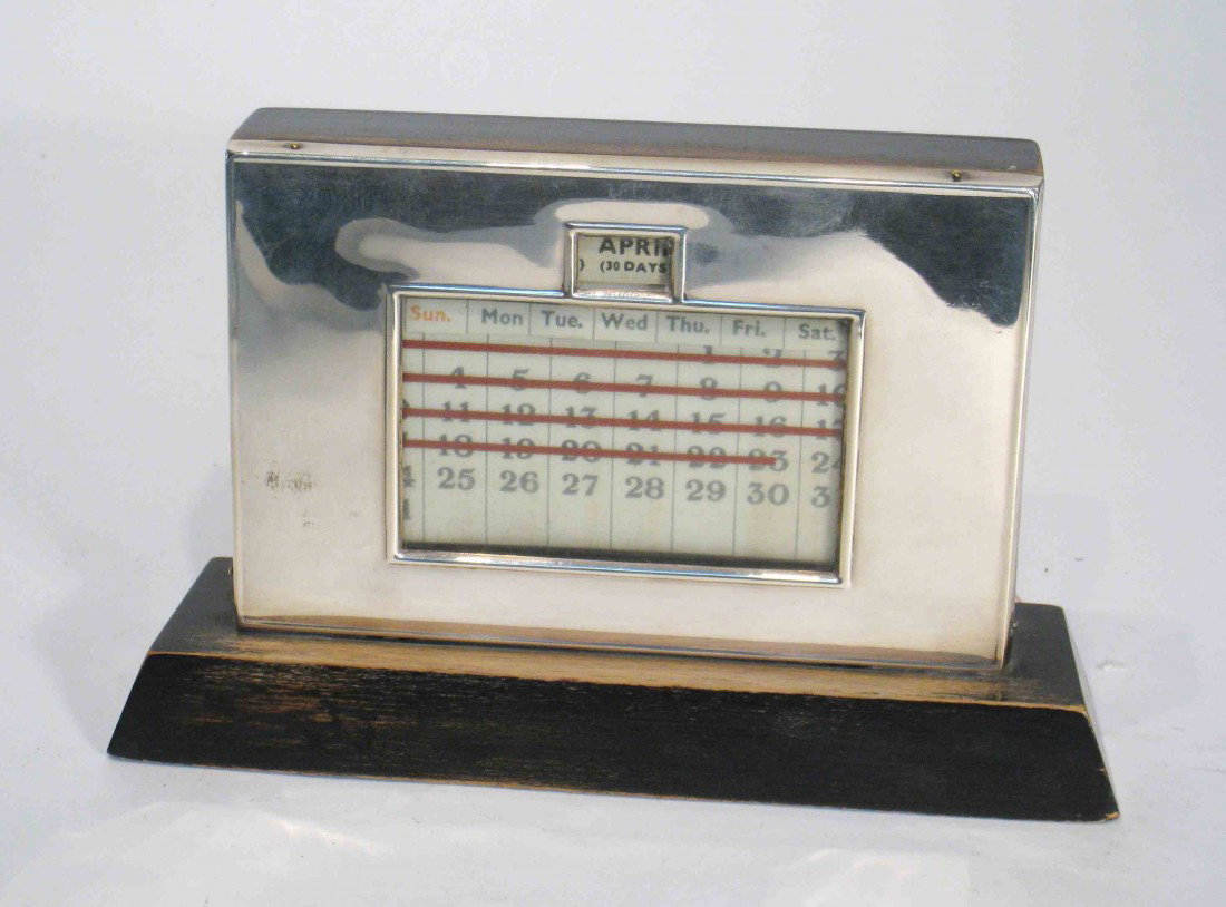 Silver And Wood Desk Calendar: A sterling silver desk calendar showing the monthly calendars and adjusted with knobs at the bottom and back.