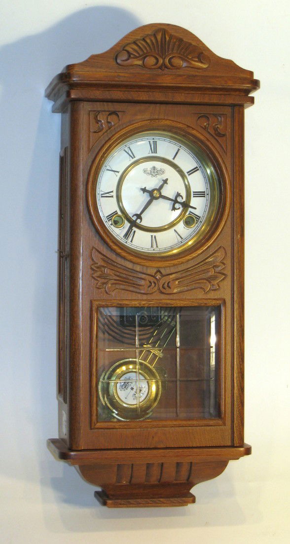 Wall Clock: An oak cased wall clock, featuring a "R-A" type pendulum striking on a gong and with an inside engraved brass plaque "Centennial Parlor Clock, No A2300".