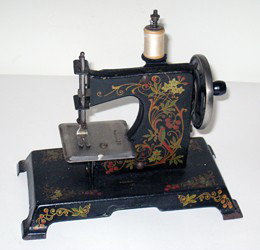 Miniature Sewing Machine: A 19th or 20th century 7" paint decorated and hand operated travel sewing machine.