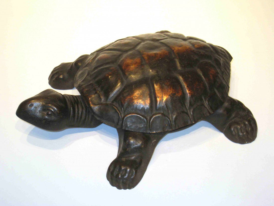 Turtle Form Spittoon: A metal turtle whose head when pushed raises up the turtle shell to reveal a spittoon.