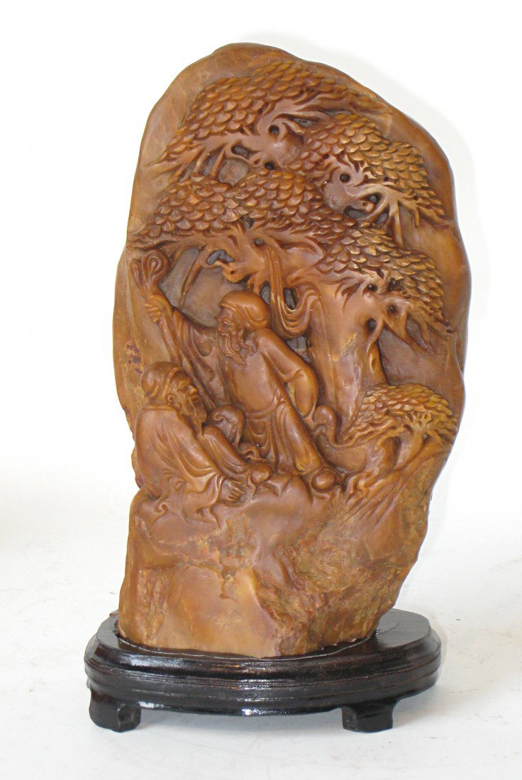 Carved Hardstone Sculpture: An impressive redstone carved sculpture set upon a custom base. There are two figures beneath trees.