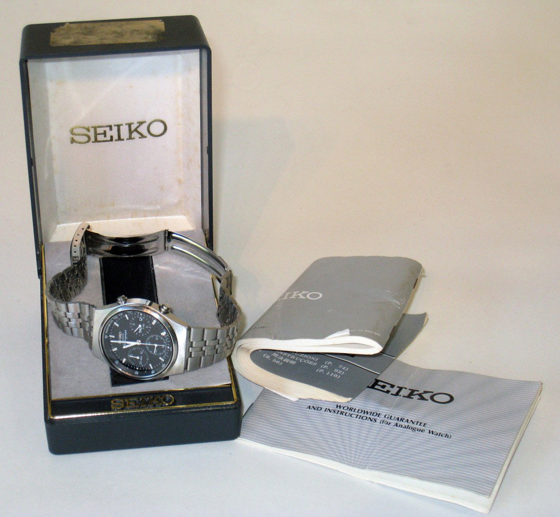 Seiko "Chronograph" Wrist Watch: A quartz watch in its original box with literature. The watch presents the date and time with a seconds hand, and a stopwatch chronograph with a separate button for elapsed time and an elapsed time fe