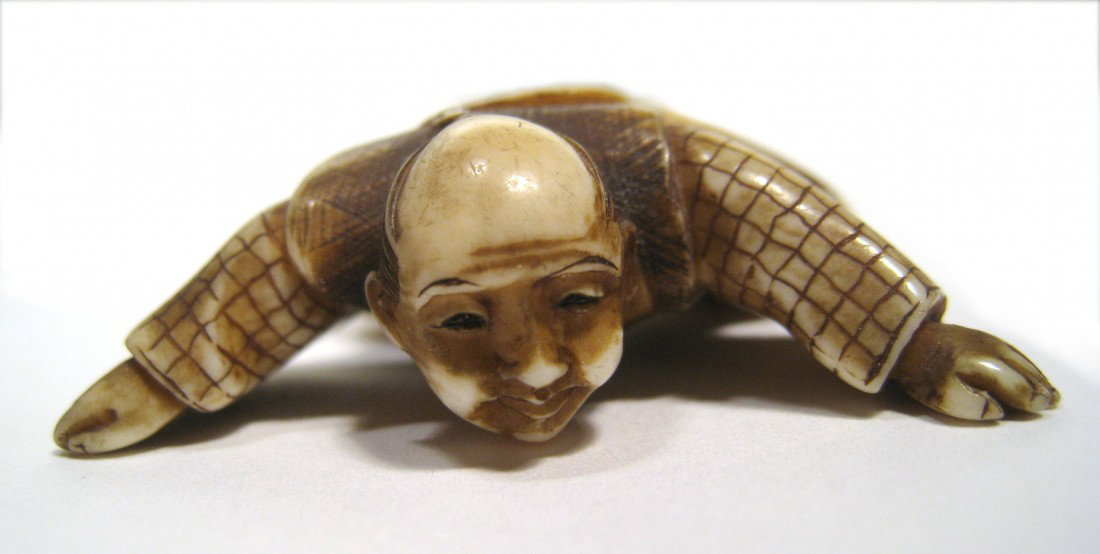 Unusual Netsuke Of Climbing Man: An engaging and unusual signed 1 1/2" X 1 5/8" Netsuke of a climbing or crouching man with spread limbs. Signed on the underside, his left knee. Shipping: We are able to pack and ship this item to an 