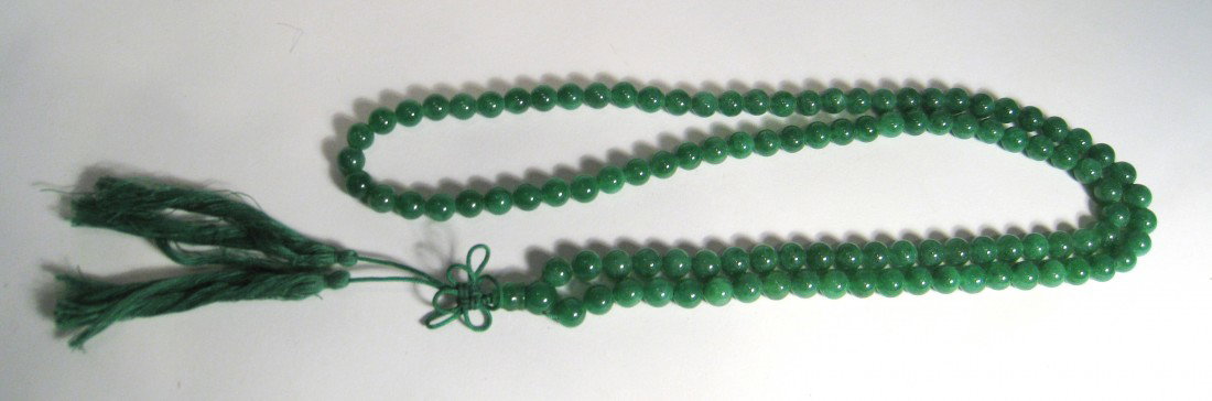 Dark Green Jade Necklace: A 17" dark green jade necklace with 1/4" beads and a knotted tassel in green string. Shipping: We are able to pack and ship this item to an address in the United States for $15.00 via USPS Priority Ma