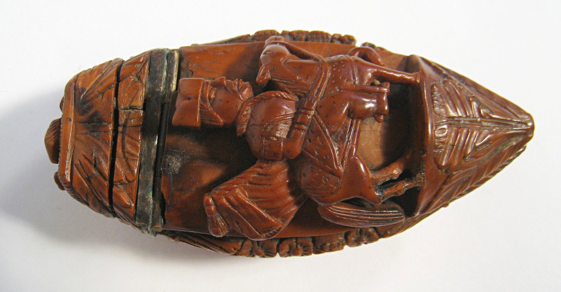 Carved Koukola Nut: A Napoleon era carved nut with a hinged lid with images of soldiers possibly depicting the Austrians. Note age crack on the bottom of base part. Shipping: We are able to pack and ship this item to an 