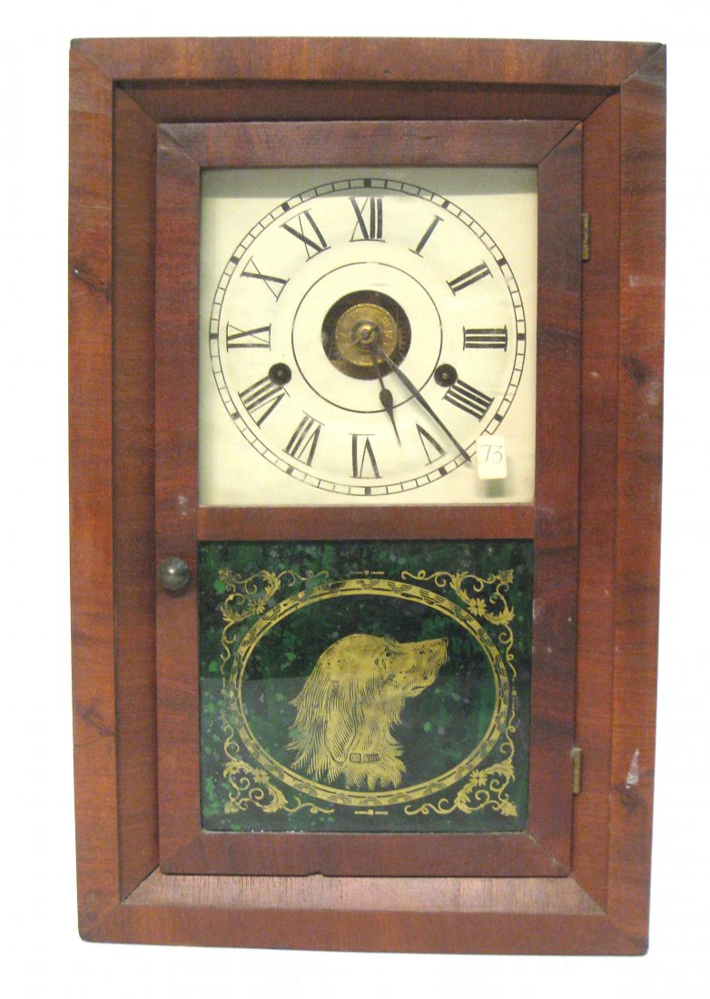 Miniature Ogee Clock: A 19" spring powered smaller ogee clock with a veneered case and showing a dog's head reverse painted glass. Shipping: We are able to pack and ship this item to an address in the United States for $50