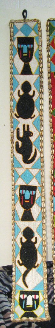 Bead Mounted Totem: A bead decorated African wall hanging or totem, 64" X 7", consisting of a hand sewn leather base with applied bead strings and bordered by shells. Shipping: We are able to pack and ship this item to a