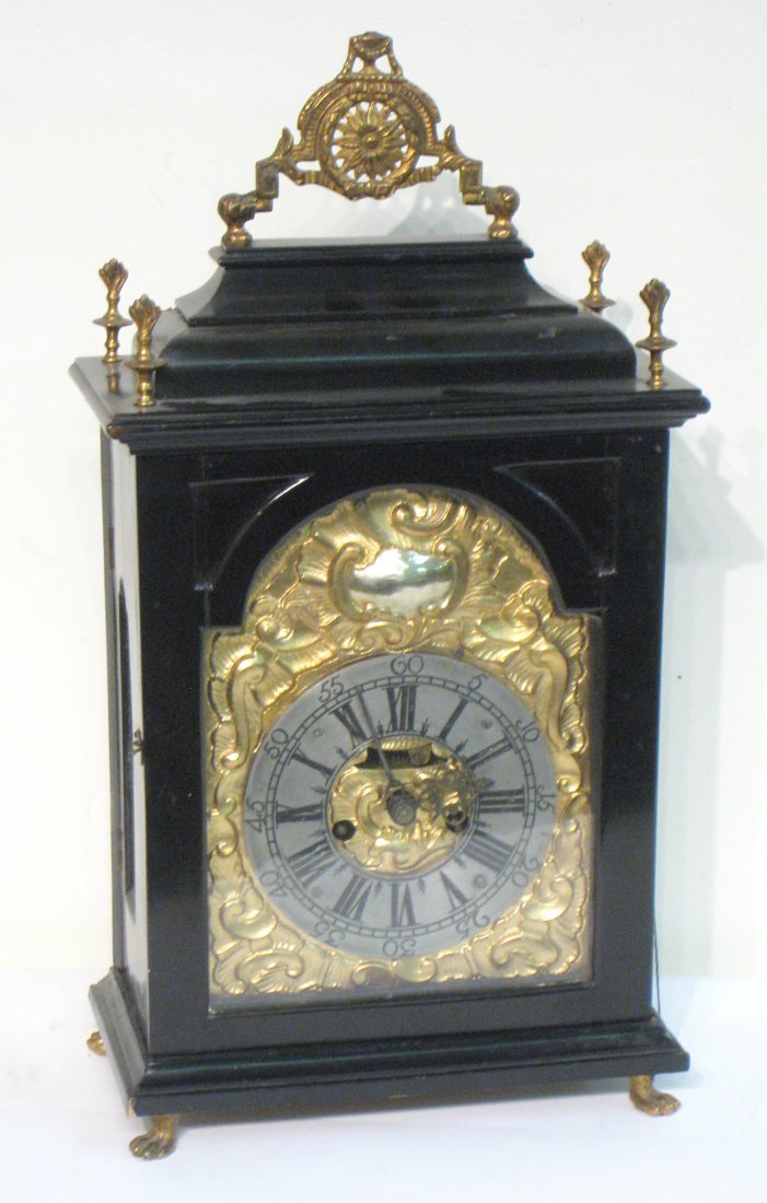 Austrian Bracket Clock: A late 18th or early 19th century crown wheel Austrian bracket clock with a gilt brass and silvered broke arch dial within an ebonized fruit wood case and with cast brass finials and other such accout