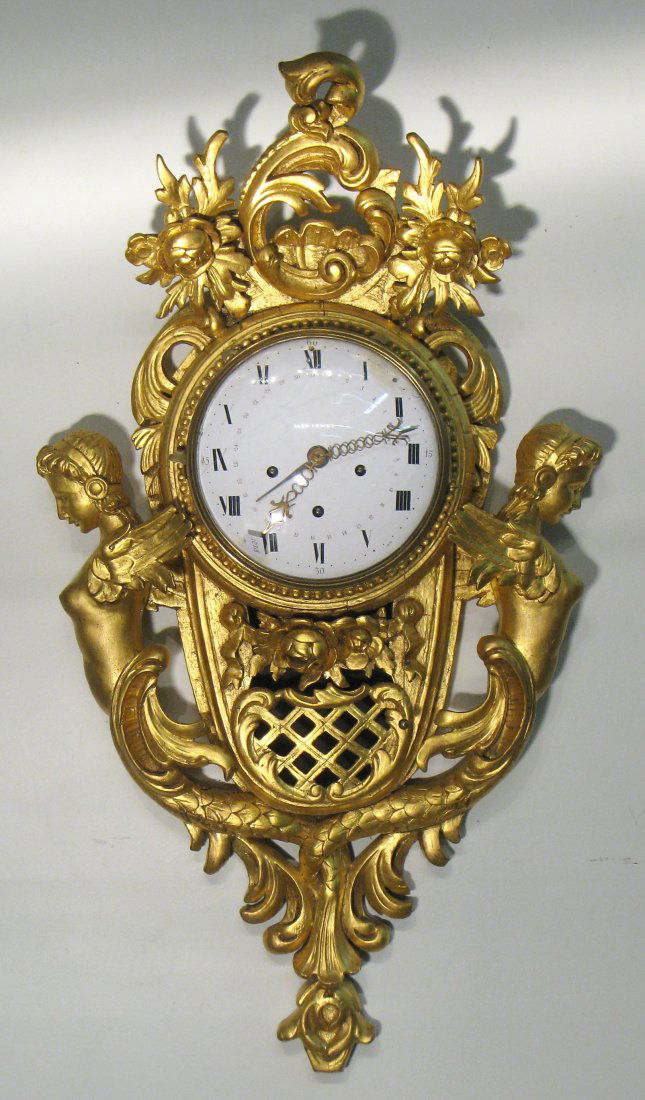 Giltwood Carved Wall Clock: A large gilt wood wall clock, in an impressive Baroque case, the back plate of the crown wheel escapement movement with a silk suspension pendulum is signed" Mathias Schotzkey, Prag". This with a porc