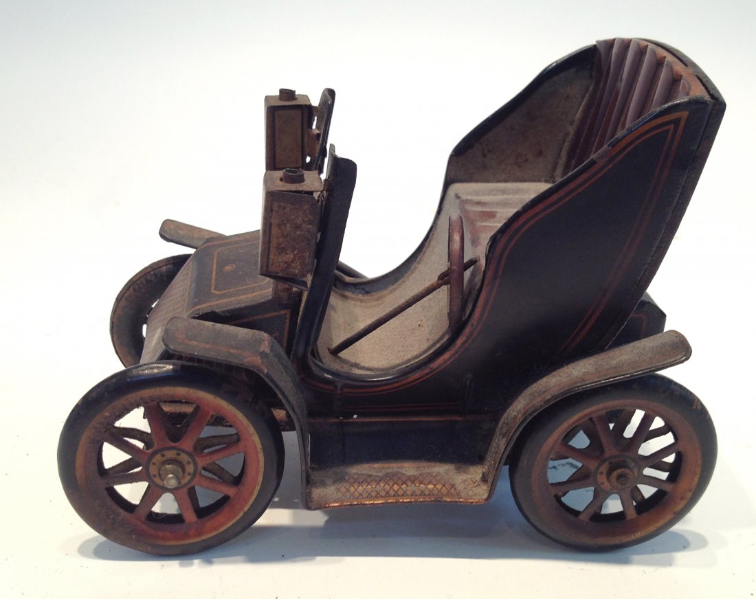 Toy Motor Coach: A 5 1/2" model toy of the earliest kind of automobile, with open air seating for two and argon (?) lamps. Nice original pinstriped painted detailing (in excellent condition), and having a friction dri