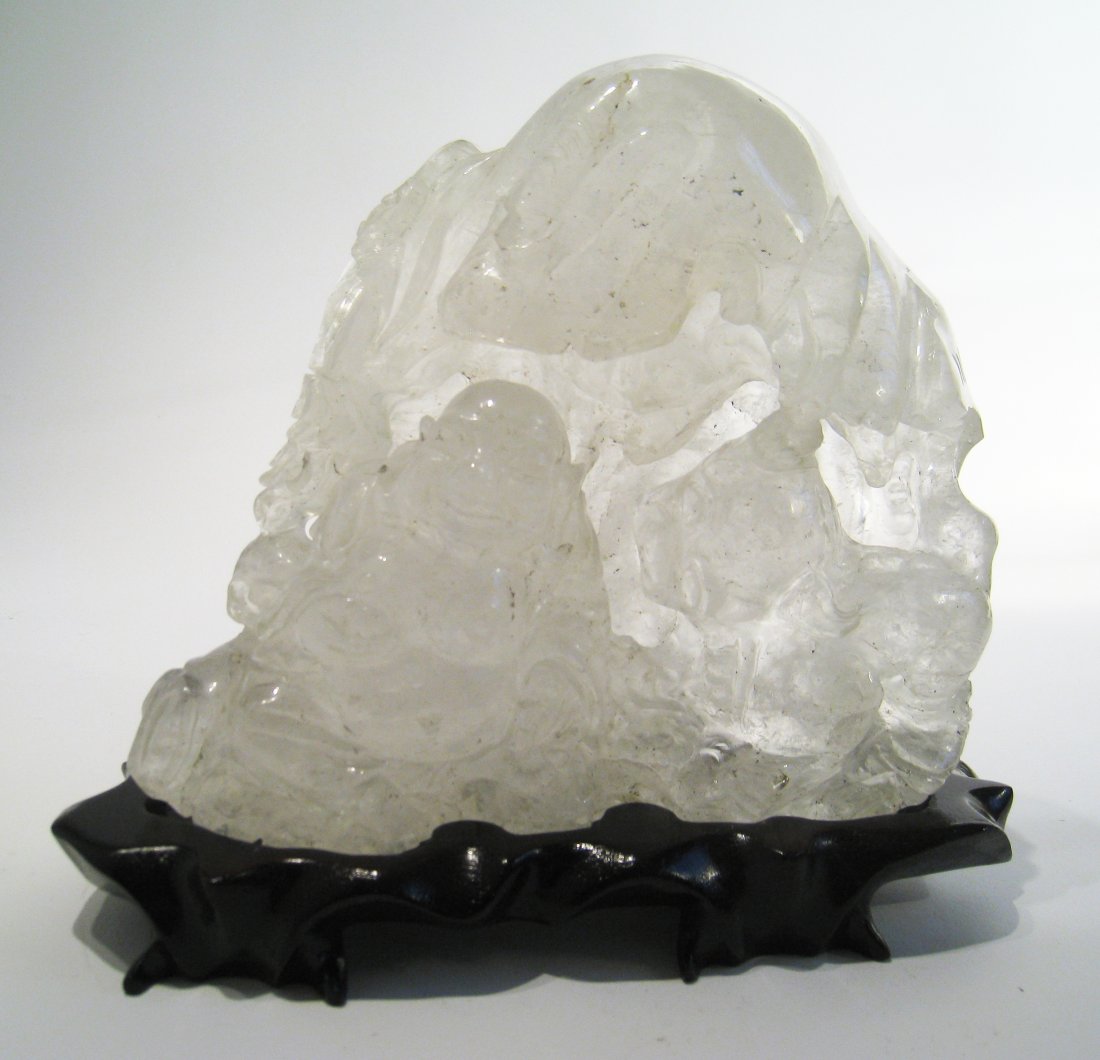 Chinese Rock Crystal Quartz Carving: A rare carved quartz display with a Buddha figure and a nearby Foo Dog within a landscape. The 5 3/4" carving weighs almost 4 1/2 pounds. Imperfections in the stone can be seen. Comes with carved wood