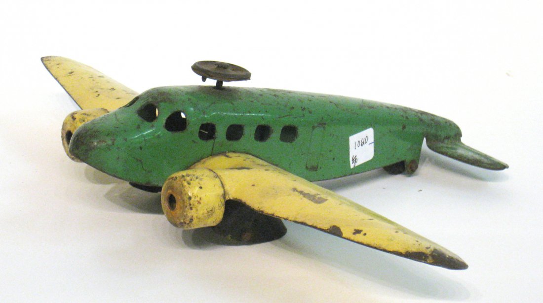 Toy Model Airplane: In green and yellow painted metal, possibly once a highbred helicopter/fixed wing aircraft but now lacking helo blades, landing gear wheels and rudder. Shipping: We are able to pack and ship this item