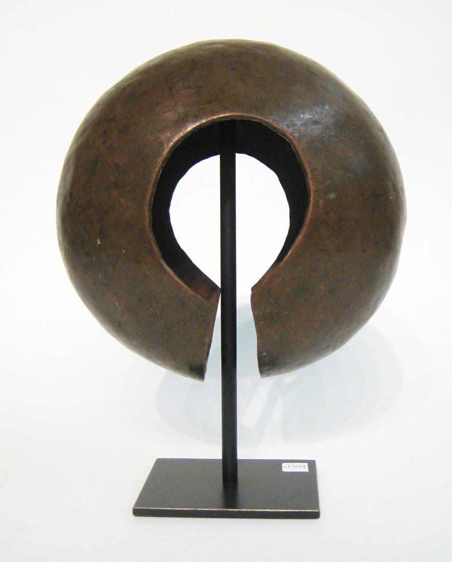 Bronze Currency Anklet, Zaire: From the M'bole culture of Zaire, 19th century. About 9 1/2" across, a hollow shell mounted onto a custom steel stand. Shipping: We are able to pack and ship this item to an address in the United Stat