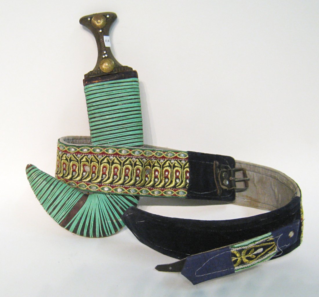 African Rhino Horn Dagger & Belt: A ceremonial dagger in a sheath wrapped in green cane, 14" in lengthy together with a 36" attached embroidered belt. The handle is possibly made of rhino horn. Shipping: We are able to pack and ship t