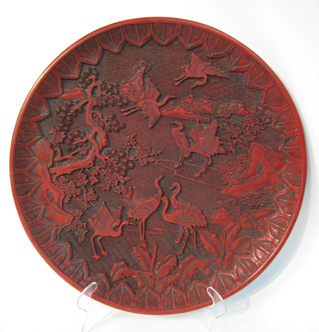 Chinese Cinnabar Charger: 13 3/4" diameter with a black lacquer back and a maker's mark. Shipping: We are able to pack and ship this item to an address in the United States for $50.00 via USPS Priority Mail or via FedEx Ground