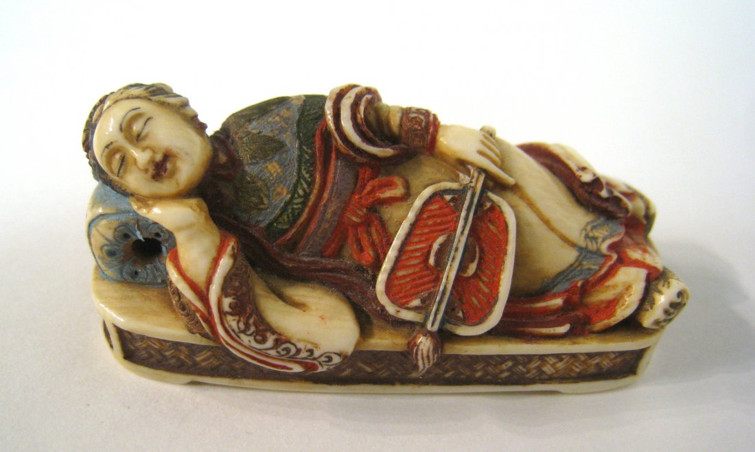 Netsuke Reclining Woman: A signed Japanese Netsuke of a reclining woman with a fan in polychrome paints. Signed on the bottom., about 2 1/4". Shipping: We are able to pack and ship this item to an address in the United States