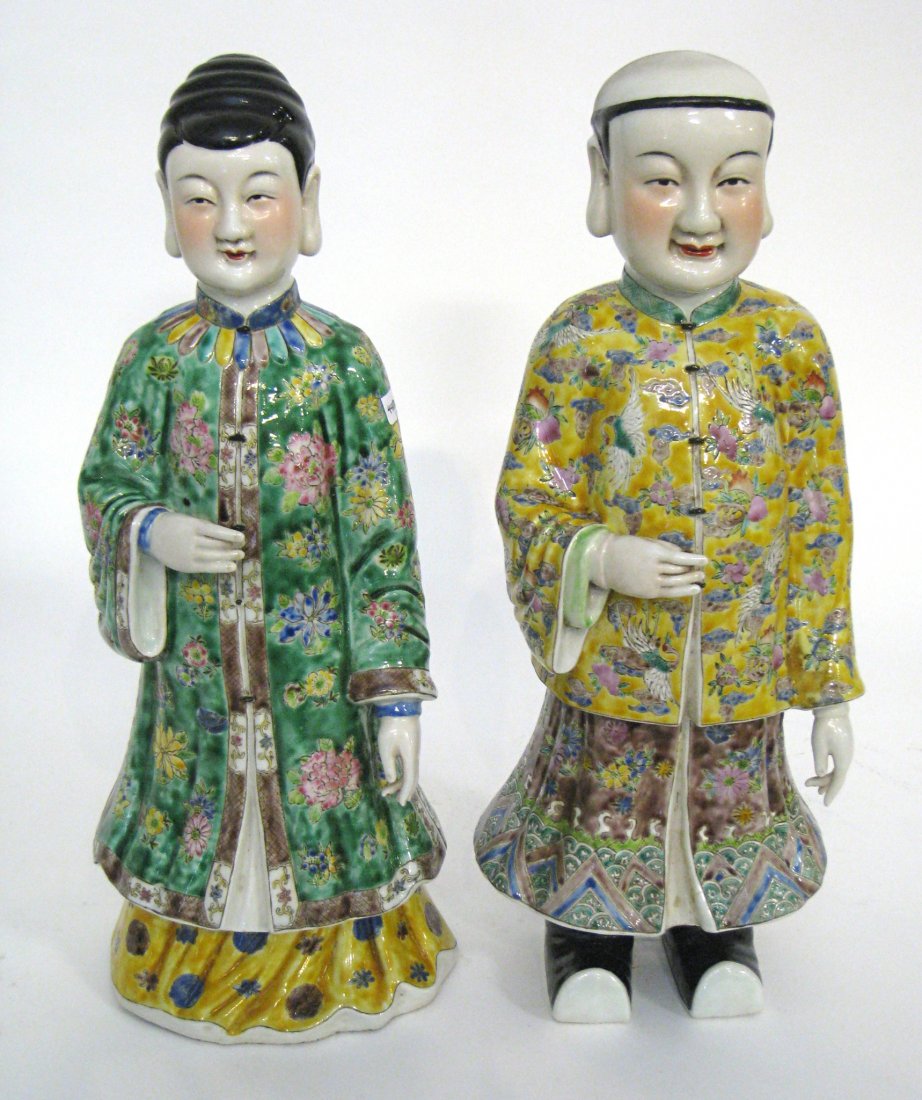 Chinese Porcelain Figures: A garniture set of 17 1/2" porcelain Chinese figures, man and woman, in sumptuous and vividly colored robes, offering friendly gestures. Shipping: We are unable to ship this item. Please contact our l