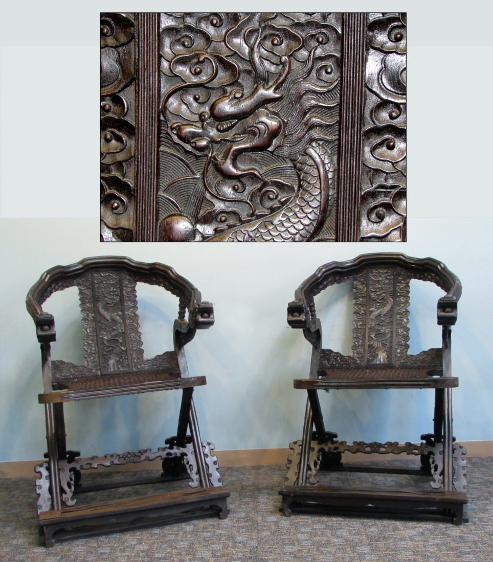 Pair Of Carved Zitan Folding Chairs: An outstanding pair of dark hardwood 19th c. Chinese folding chairs with molded undulating armrests terminating with lunging Dragon heads and with carved-in loose balls in their mouth. Exceptionally w