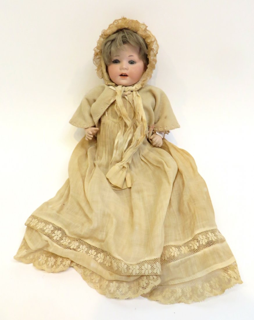 French Bisque Baby Doll: A 10" doll wearing a white embroidered vest or cape, a long linen gown with lace and head gear. Bisque head with glass eyes and partially opened mouth. Only one leg :-( . Shipping: We are able to pack