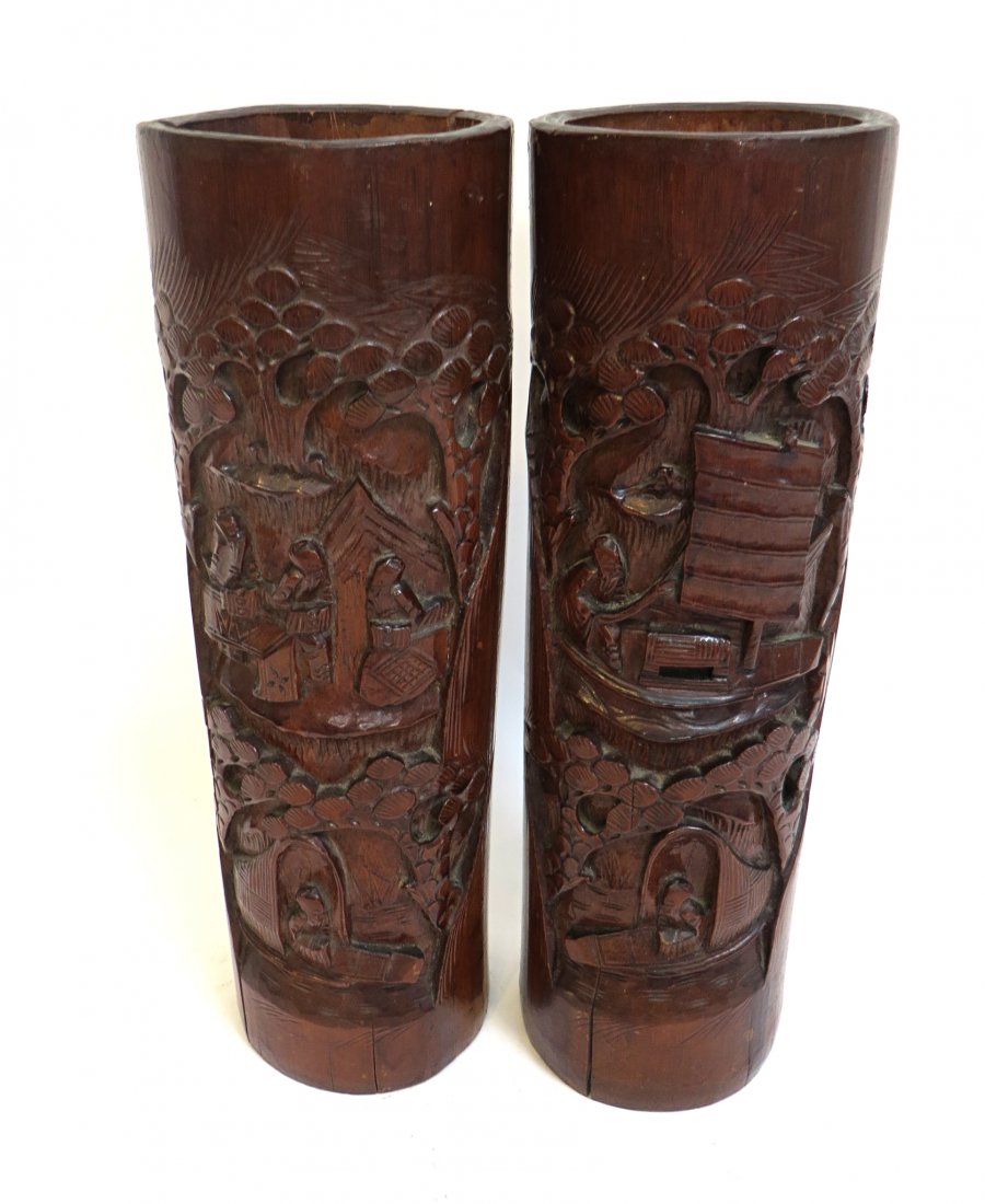 19th Century Bamboo Garnitures: A pair of 13 1/2" bamboo carved garnitures in dark brownfrom age and finish with depictions of seascapes with boats and a landscape. Note that due to age and wood shrinkage each garniture vase is spli