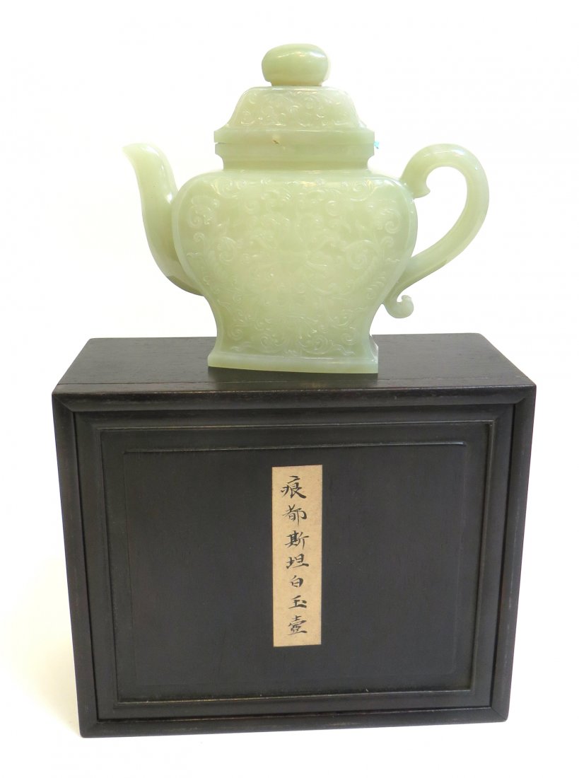 White Jade Tea Pot In Zitan Box: 5 3/4" teapot within a custom Zitan wood presentation box, bas carved onto the body with a flowing design suggestive of a floral pattern. Two relatively minor flaws in the stone are noted on the teapo