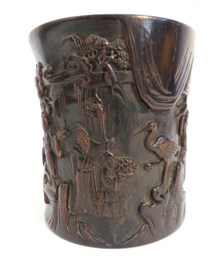 Zitan Carved Brush Pot: Zitan Carved Brush Pot: On this cylindrical carved brush pot, monks offer food and peaches in an outdoor setting that includes a wading bird. A tea set is placed on boulders and a house is seen in th